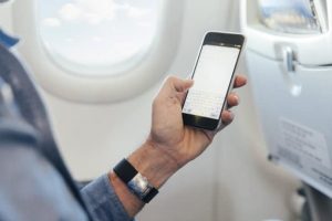 Man sitting on an airplane holding smartphone
